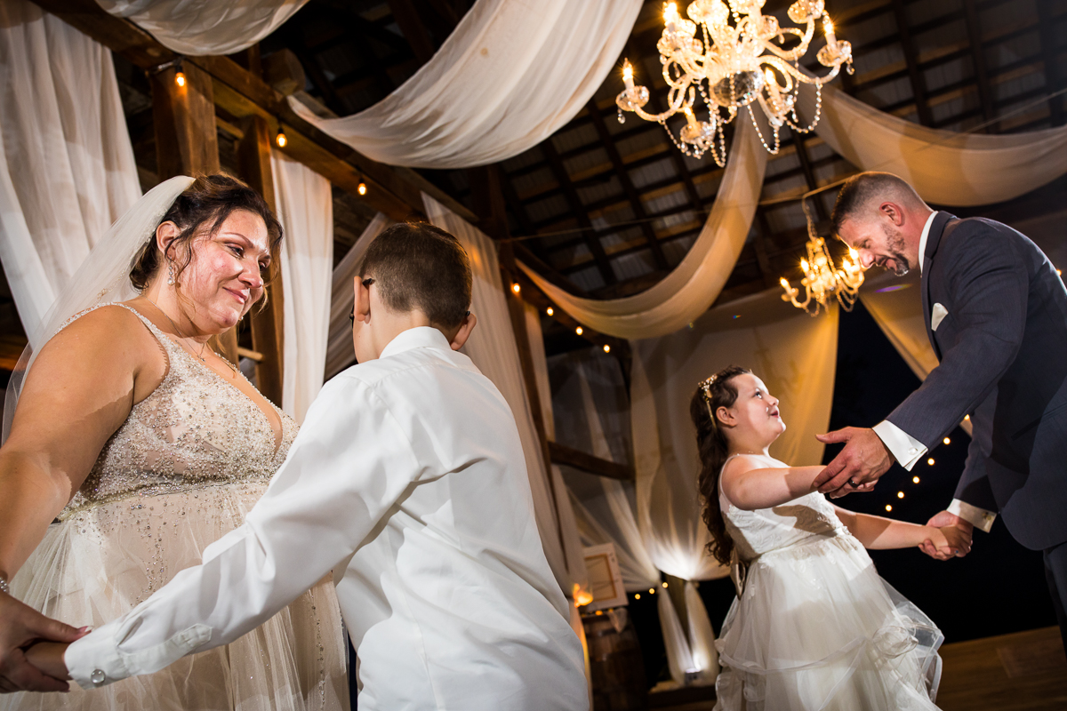 bride and groom dancing with kids during family first dance