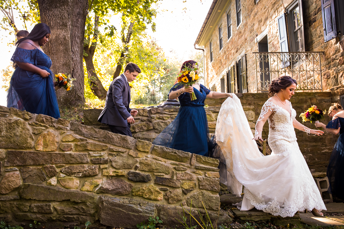 bridesmaids hold bride's train as they walk to pictures