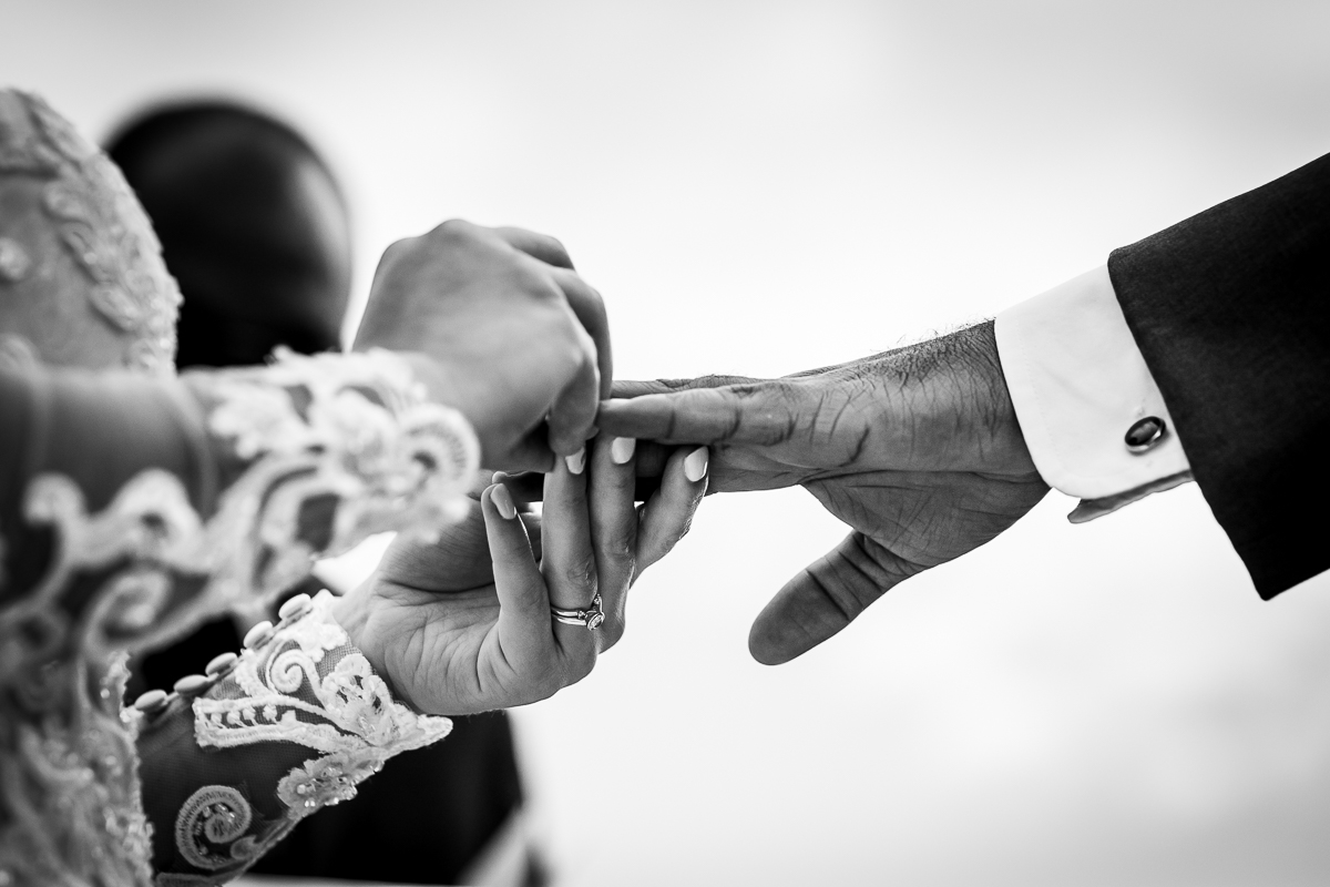 black and white photo of bride putting ring on grooms finger