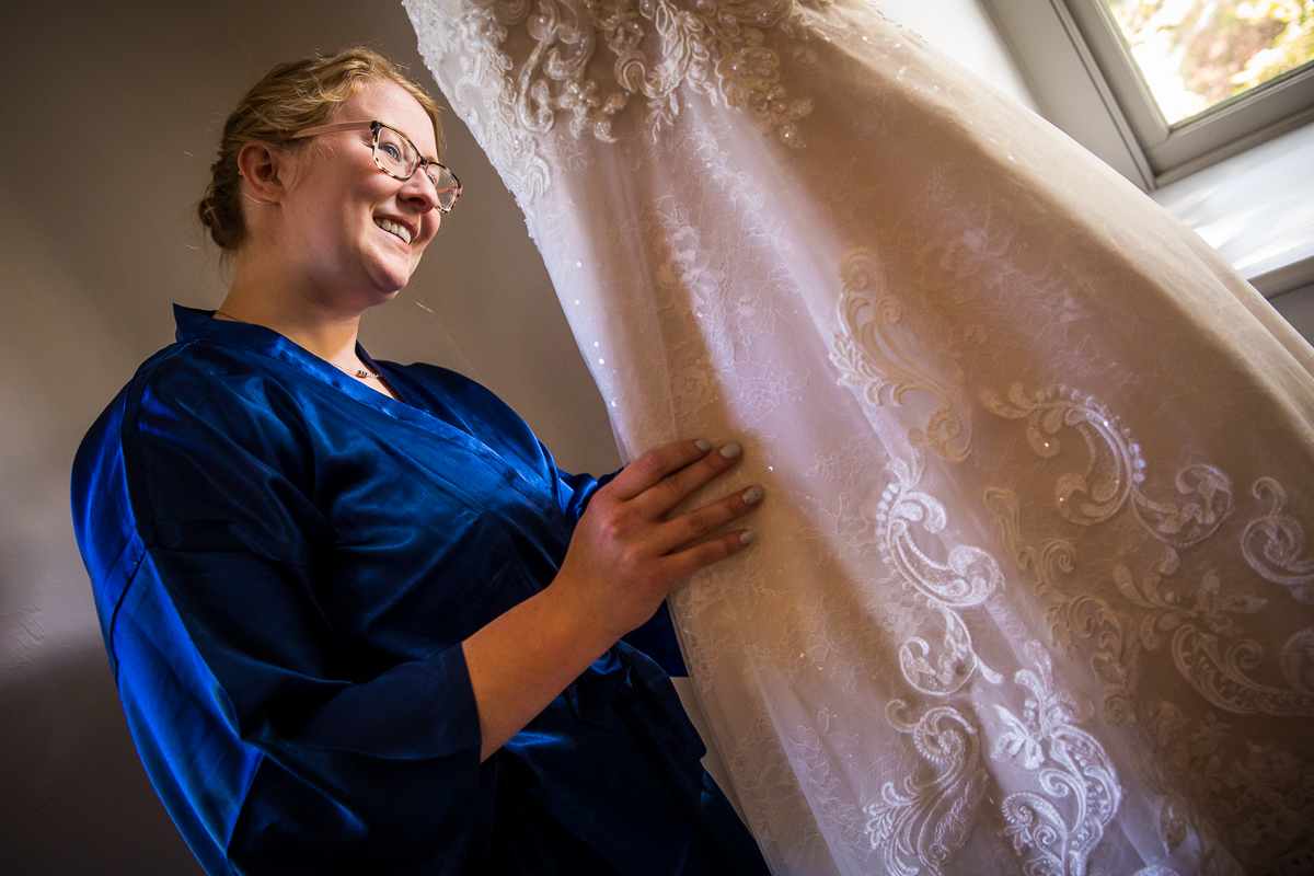 bridesmaid looking at bride's wedding dress standing in blue robe