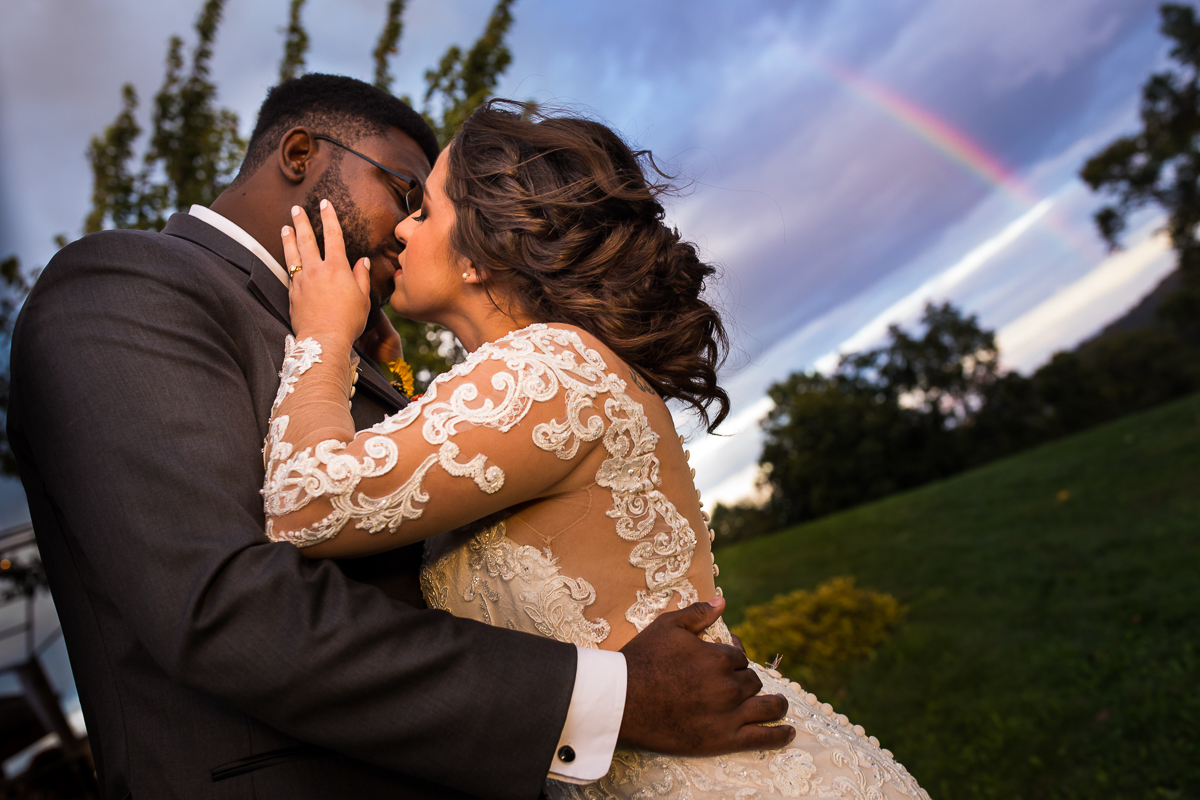 bride and groom lean in for a kiss under rainbow at hauser hill event center wedding 
