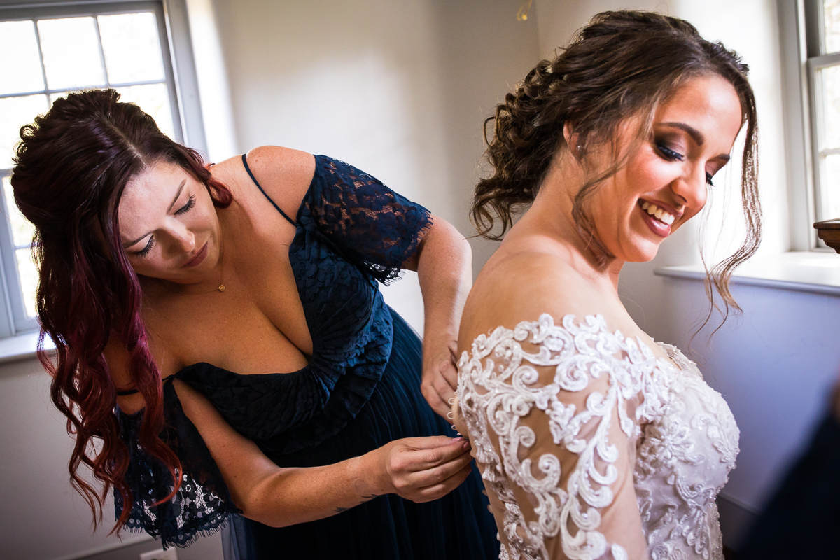 bride's sister helping button bride's wedding dress before ceremony 