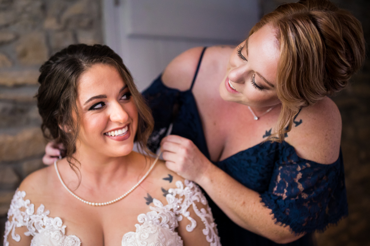 bride's sister putting necklace on her before ceremony