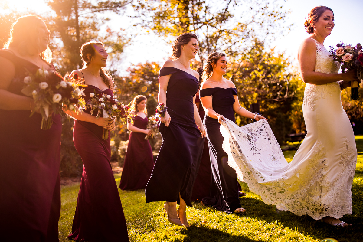bride walking with bridesmaid following behind holding dress and bouquets