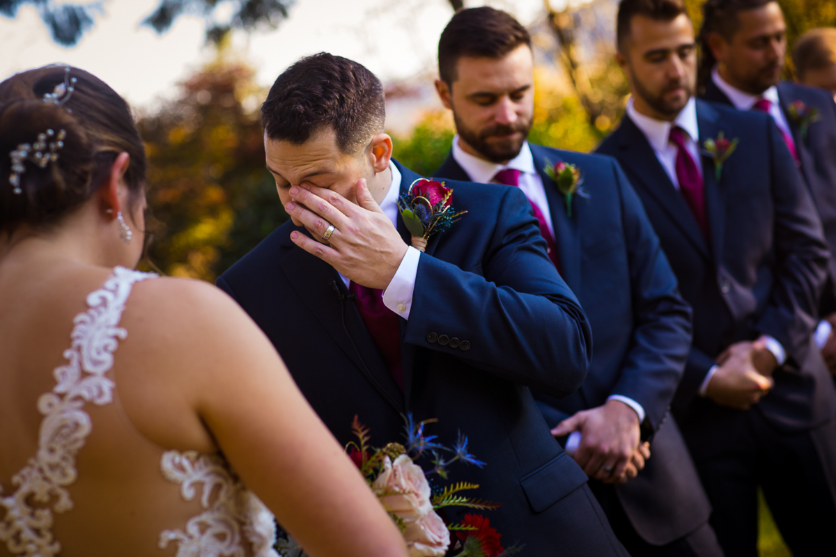 authentic candid emotional photo of groom wiping eye during wedding ceremony 