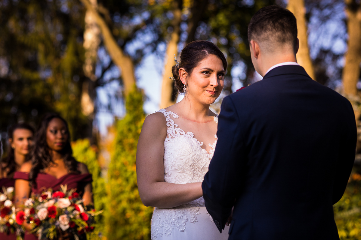 bride and groom holding hands looking at each other during ceremony with bridesmaids in background