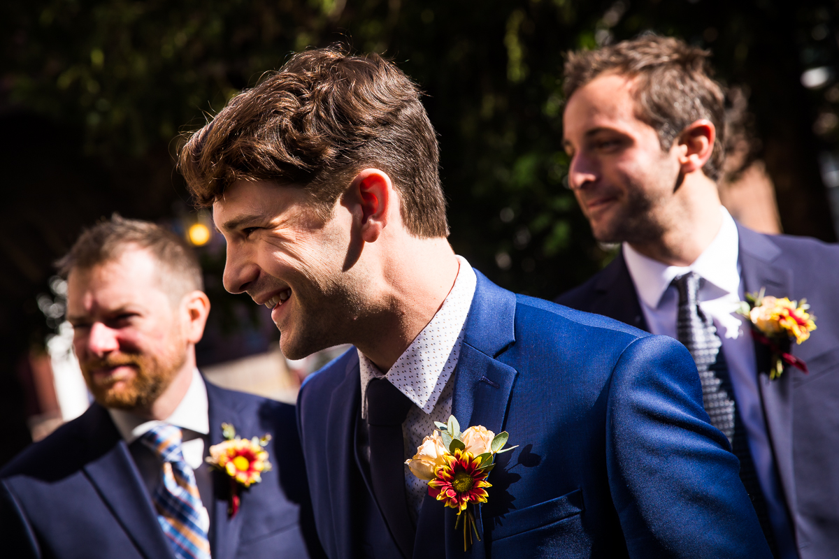 Candid photo of the groom smiling away from the camera during the wedding ceremony