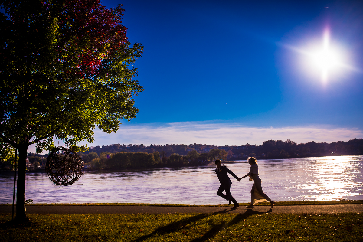 Vibrant colored image of the couple as a silhouette running down the sidewalk near the Susquehanna River for their Civic Club of Harrisburg wedding photos