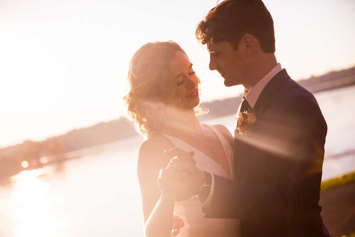 Candid photo of the couple dancing together outside for this Susquehanna Riverfront wedding with the sunset shining into the camera