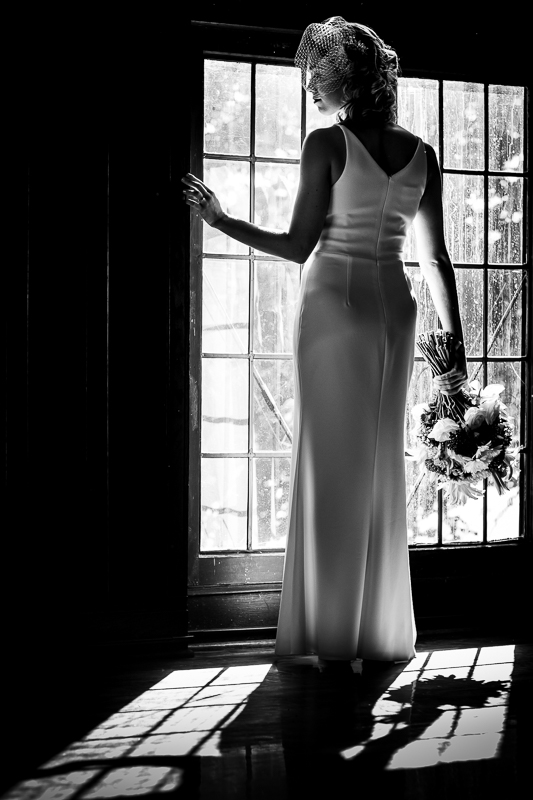 Black and white classy portrait of the bride standing in her wedding dress in the window with her flowers before her Civic Club of Harrisburg wedding