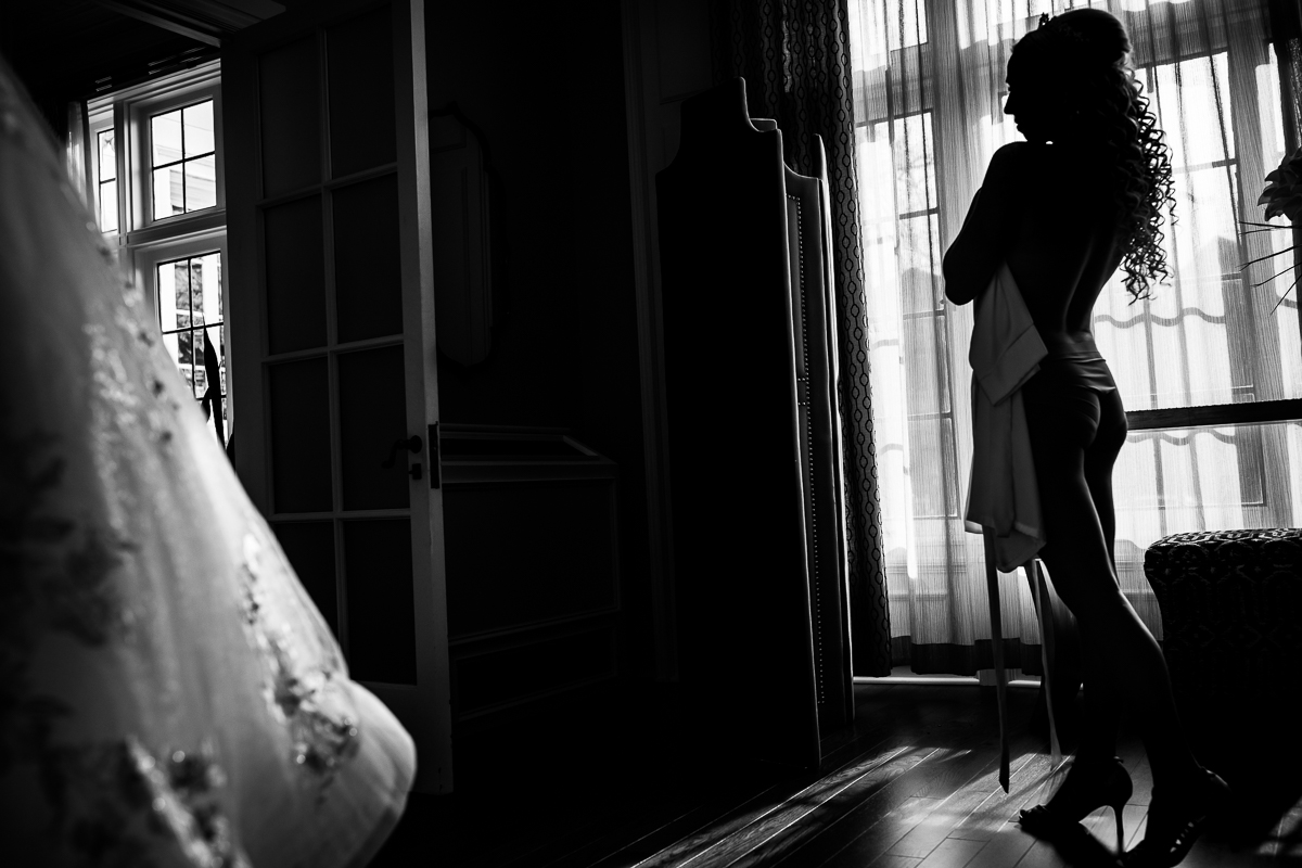 Black and white photo of bride's silhouette getting ready for her wedding