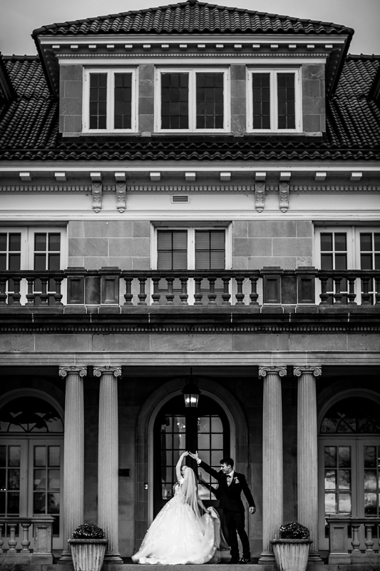 Black and white photo of the Bride and Groom dancing underneath the covered porch area outside of Kings Mansion Harrisburg