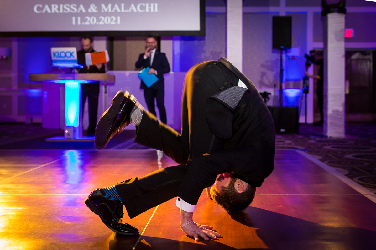 Photo of a guest doing a headstand on the dance floor at the wedding reception at Best Western Harrisburg with a colorful background