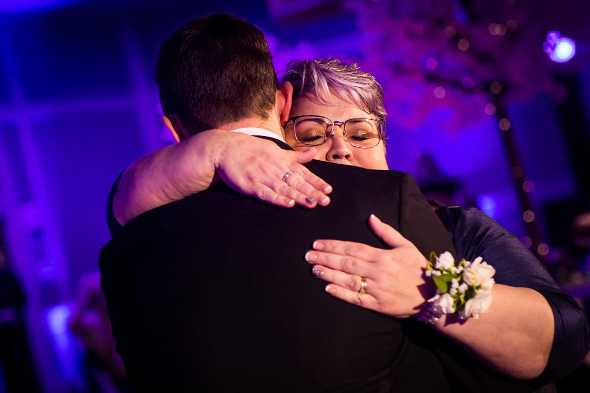 Colorful photo of the groom and his mom having a mother son dance together and hugging each other at best western Harrisburg wedding reception