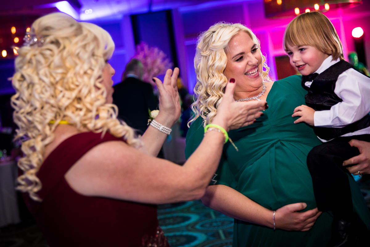 Colorful photo of the bride's mom and sister dancing together with a young child at the wedding reception