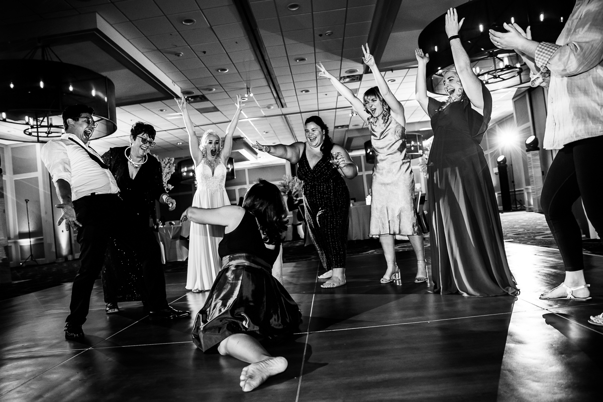 Black and white photo of guests dancing together with one of the guests on the floor dancing at the wedding reception at Best Western Harrisburg