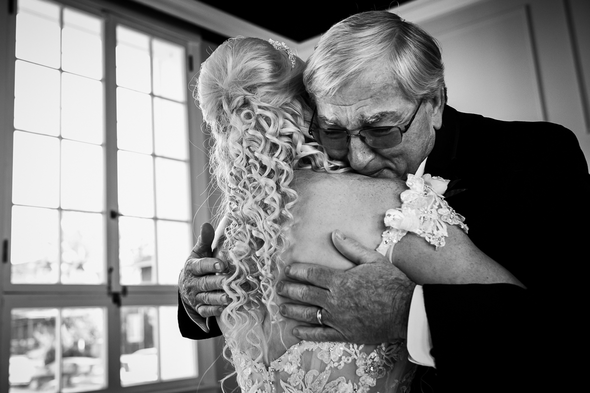 Black and white photo of bride and the father of the bride hugging during their first look