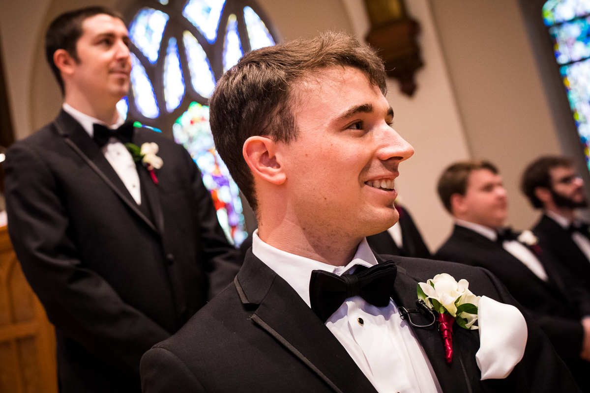 Groom smiling and admiring the bride as she walks down the aisle for their wedding ceremony at First United Methodist Church in Hershey 