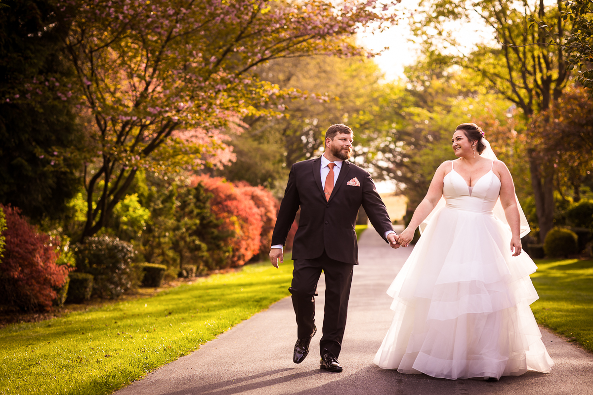 This linwood estate wedding image features the bride and groom walking down the driveway holding hands looking at one another