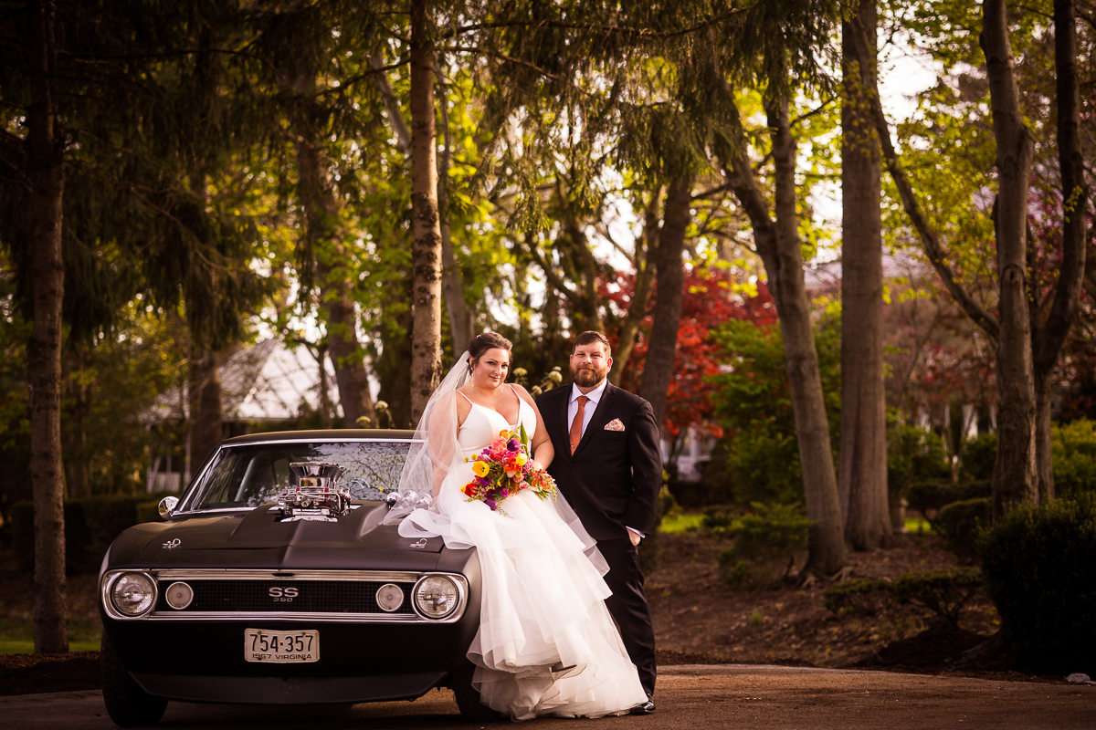 colorful, unique image of the bride and groom posing with their 1967 SS Camaro for photos after their linwood estate wedding ceremony