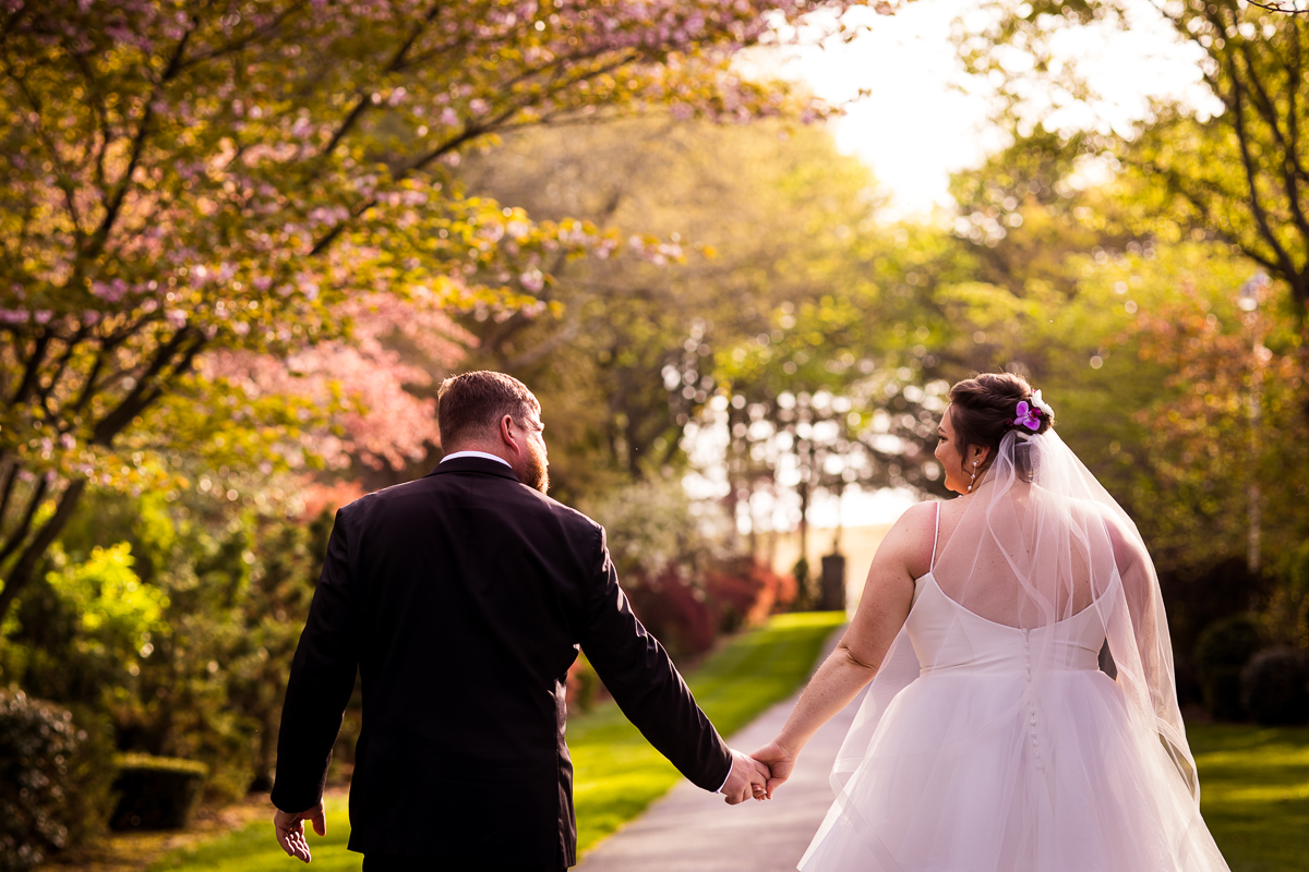 candid image of the bride and groom walking away from the camera together smiling at each other and holding hands after their wedding ceremony in carlisle pa