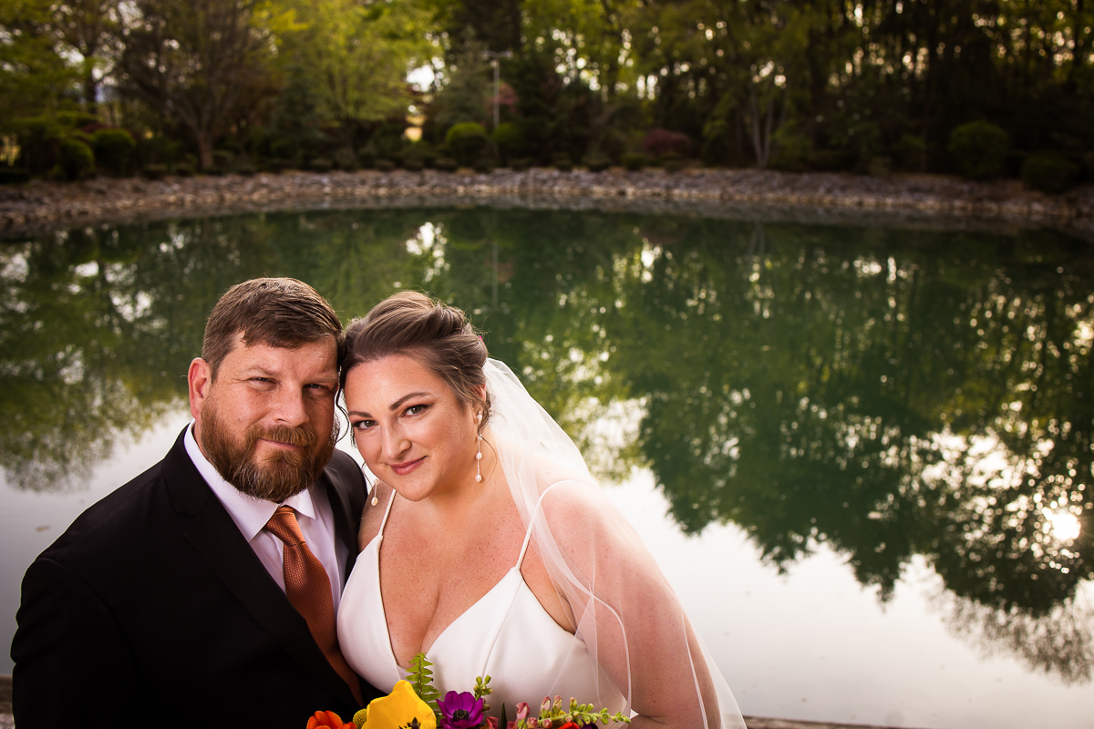 unique image of the bride and groom smiling at the camera with a pond behind them for this linwood estate wedding 