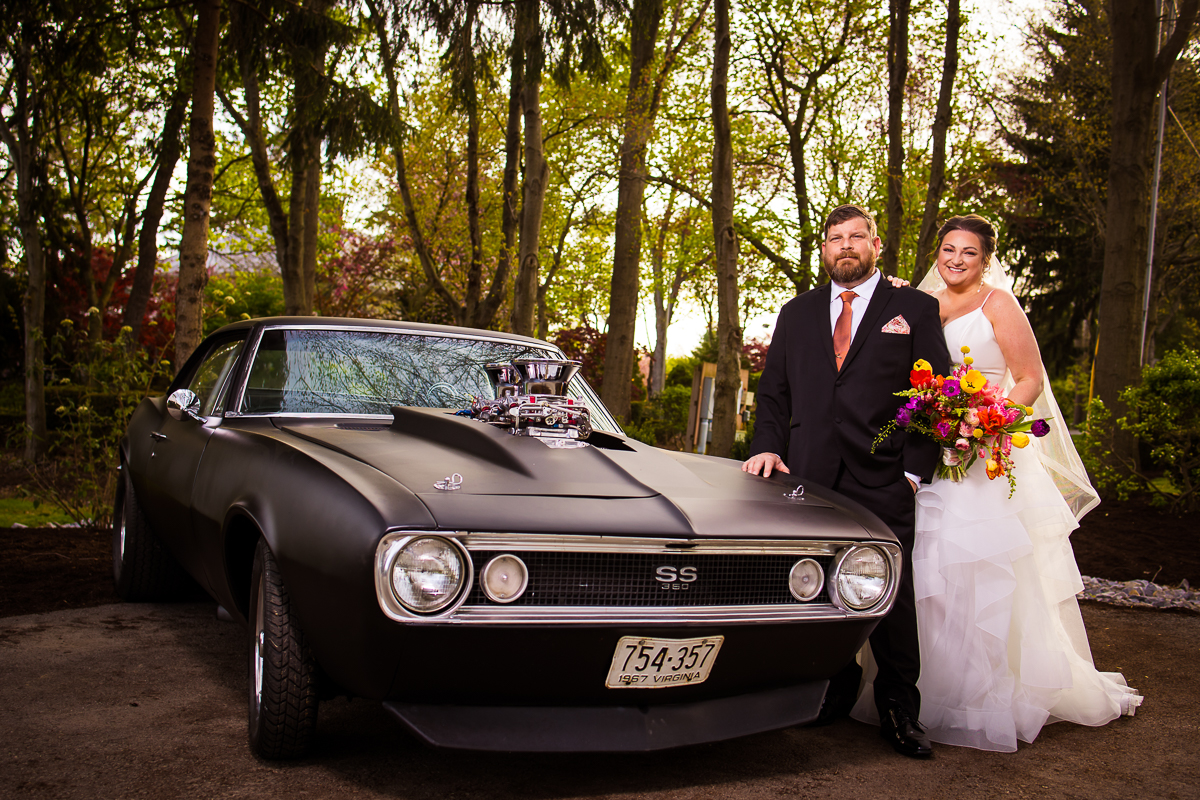 Unique image of the couple standing with a 1967 SS Camaro for their wedding photos after their Linwood estate wedding ceremony