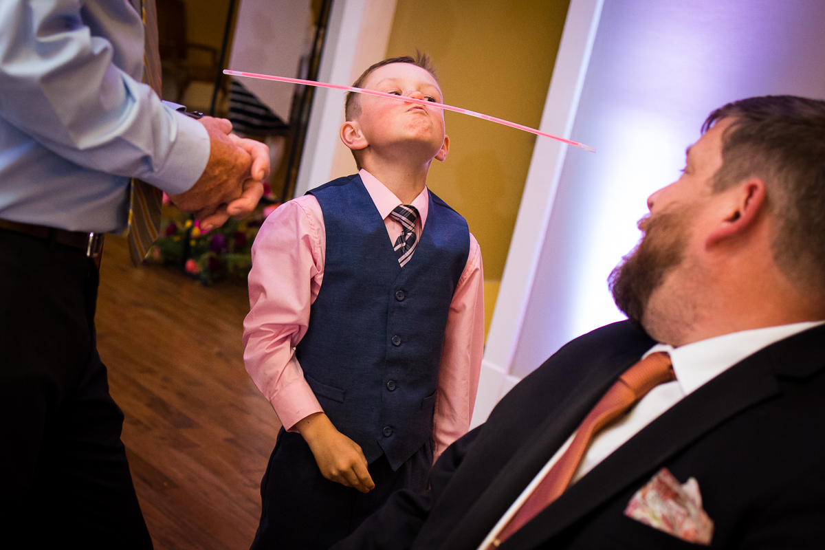 image of a little boy balancing a glow stick on his face during this Linwood estate wedding reception