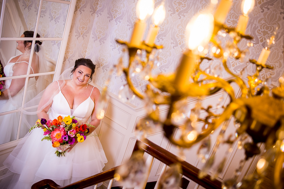 Creative, unique image of the bride smiling at the camera with a chandelier in the right corner for her preparation photos before her wedding at linwood estate
