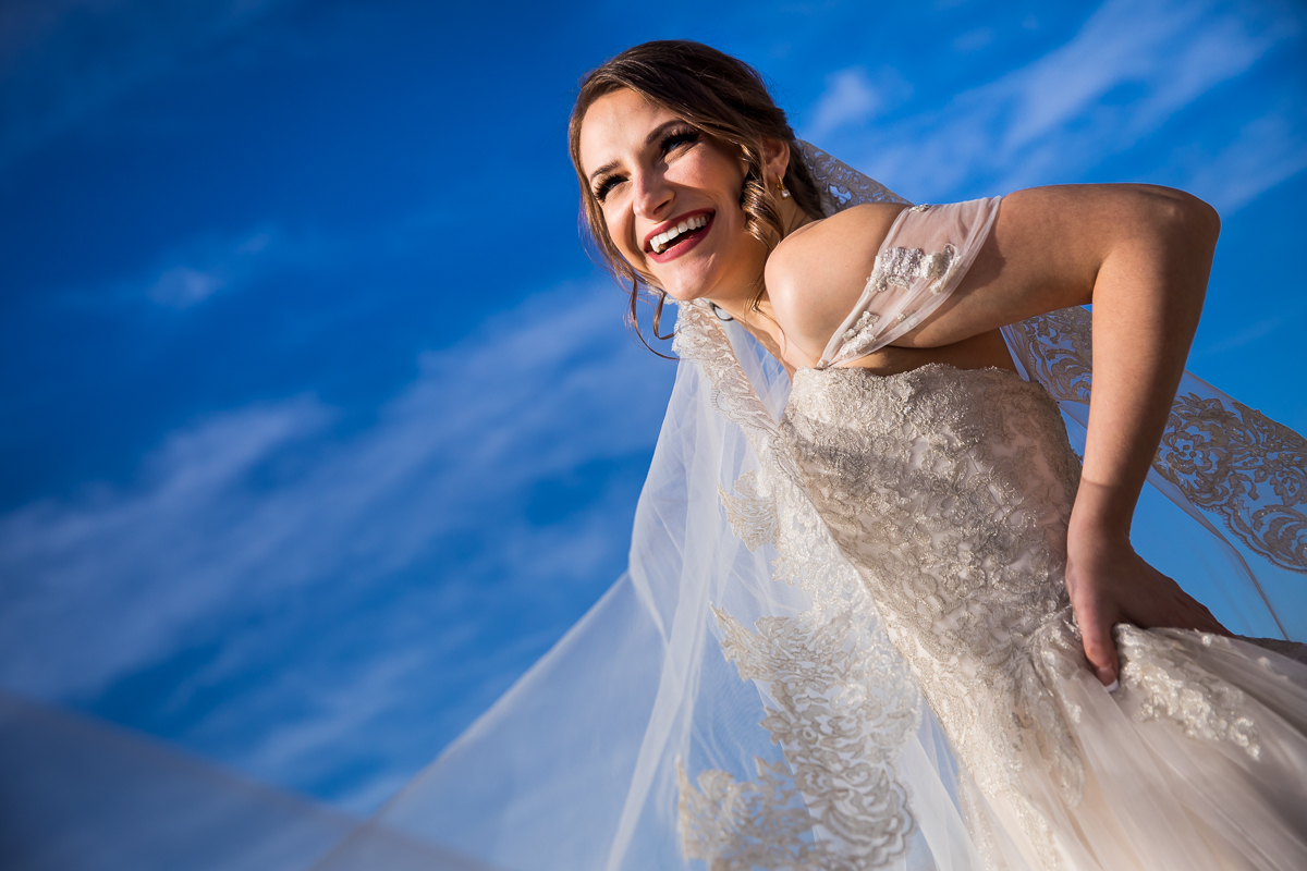 Vibrant blue sky backdrop withe the bride smiling in her dress and her veil behind her at her Liberty Mountain Resort wedding