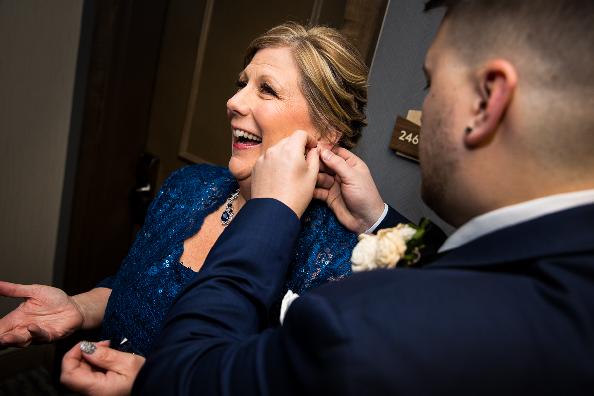 Image of the groom putting in his mom's blue earrings before this liberty resort wedding ceremony