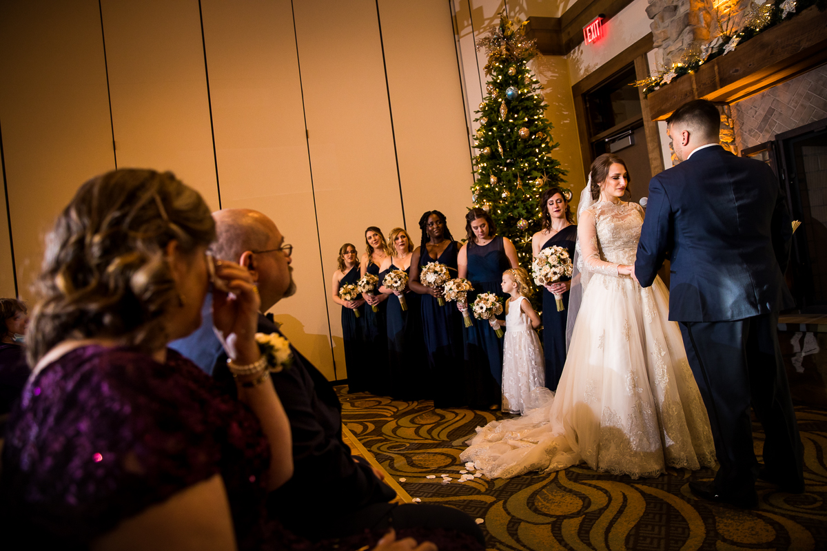 image of the bride and groom holding one another's hands as the mom cries and wipes her tears away with a tissue for this Liberty mountain resort wedding ceremony