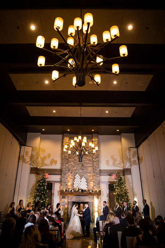 creative, unqiue image of he bride and groom holding hands with giant chandeliers over their head inside of liberty mountain resort