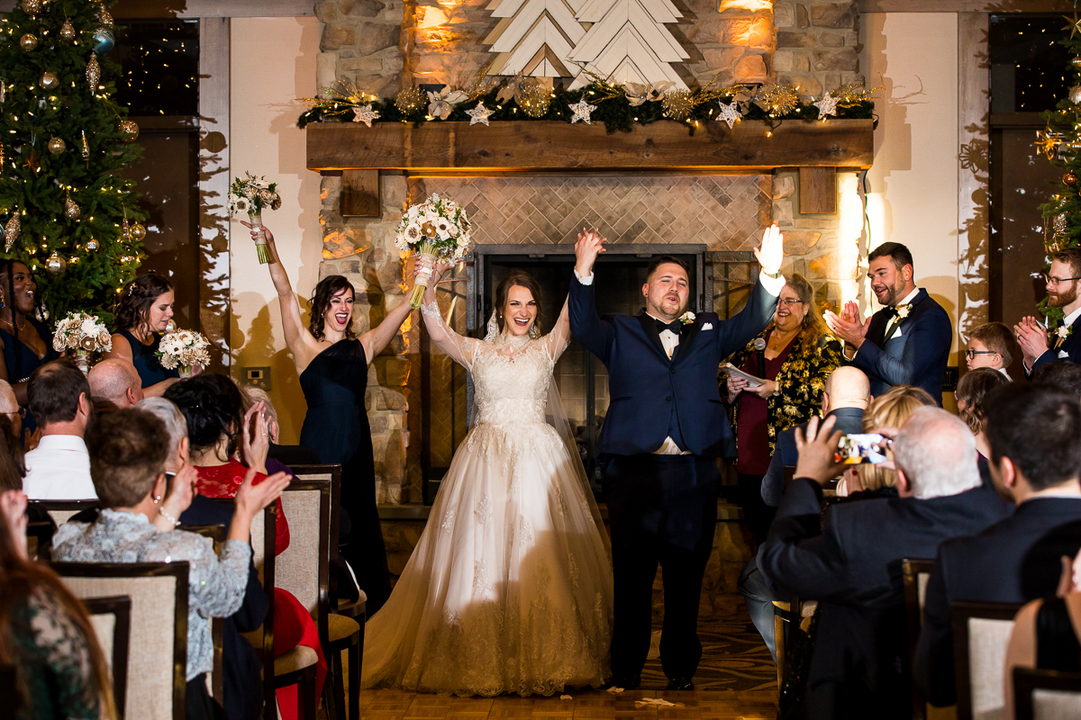 the bride and groom cheering and smiling with their hands up and they walk out together from their ceremony as the wedding party and guests cheer also for this liberty mountain wedding 