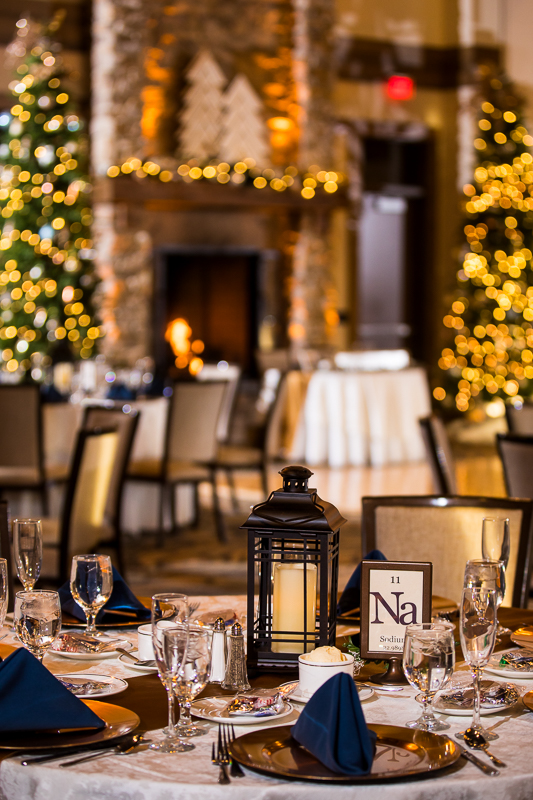Detail photo by Lisa Rhinehart during this liberty mountain resort wedding reception of the table decor with Christmas trees and decorations in the background