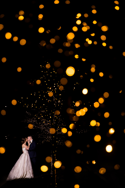 Unique, creative photography done by creative pa wedding photographer lisa rhinehart of the groom and bride kissing with gold reflections of the lights in the tree surrounding them at this liberty mountain resort wedding 