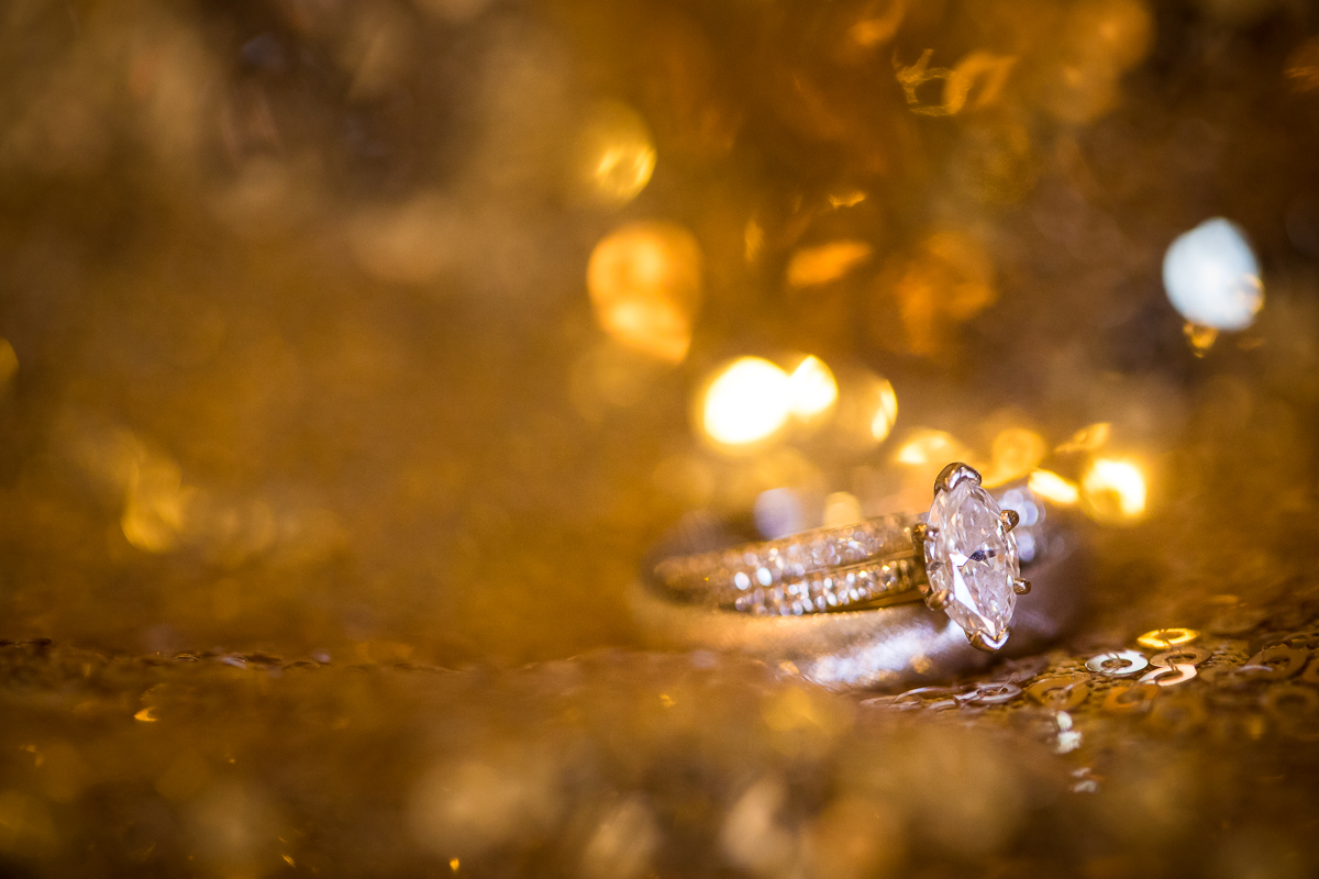 Unqiue detail photography done by Rhinehart Photography of the wedding rings in the gold sequins with the gold sequin reflections