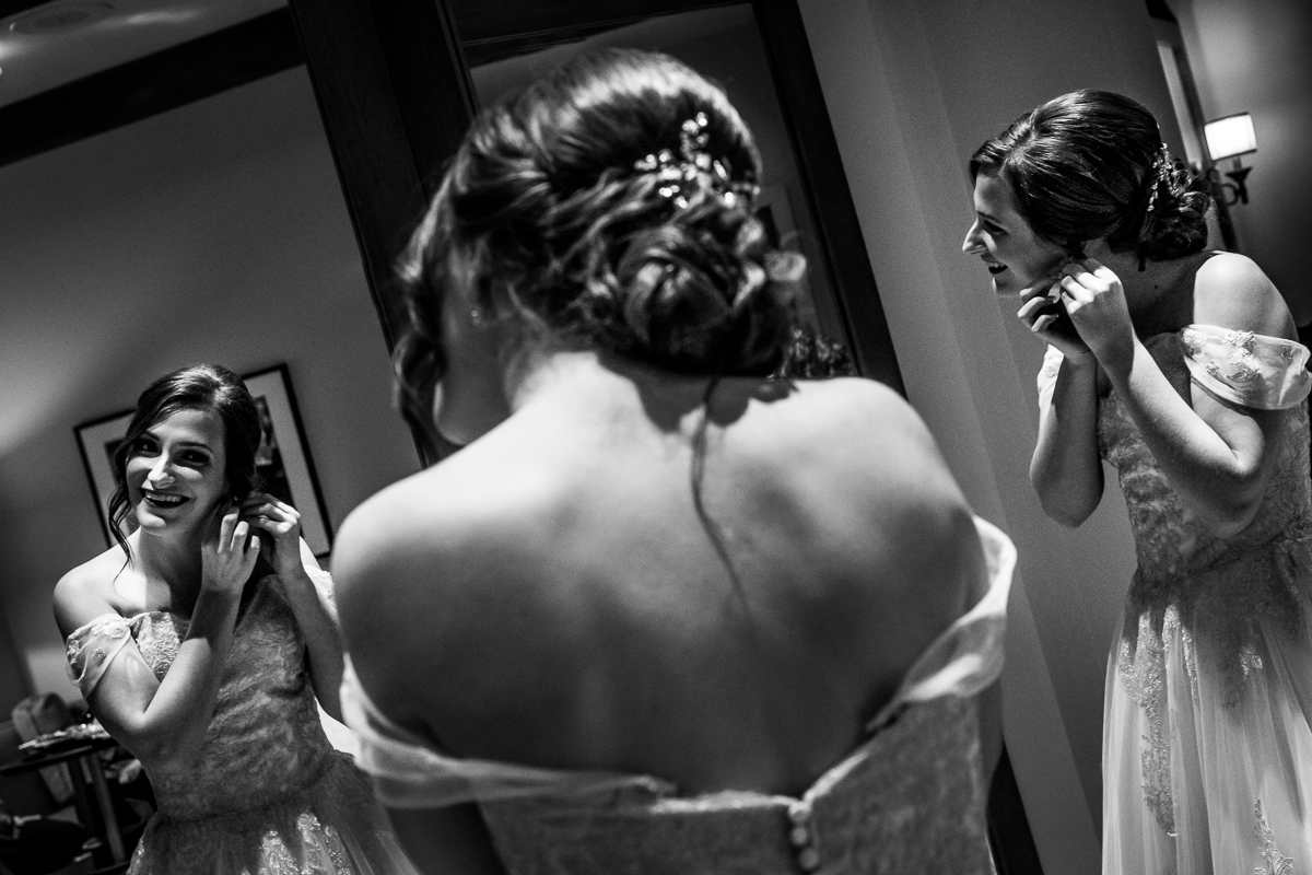 Black and white image of the bride looking at herself in the mirror smiling as she puts her earrings in before her liberty mountain wedding ceremony