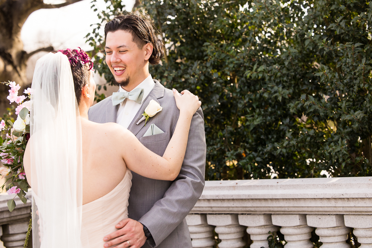 image of the bride and groom hugging one another and smiling as they see each other for the first time during their first look outside of the palace in new jersey 