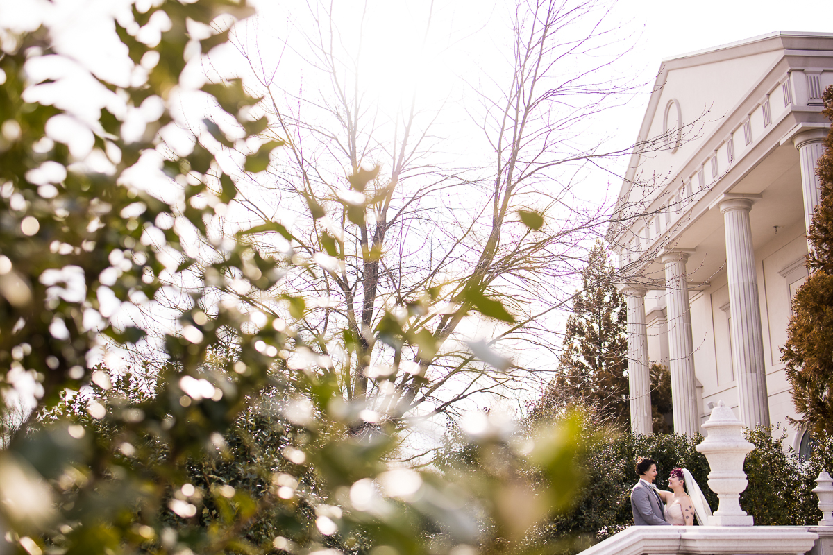 creative, unique image of the bride and groom hugging one another as they are surrounded by trees as they stand outside of the palace wedding venue