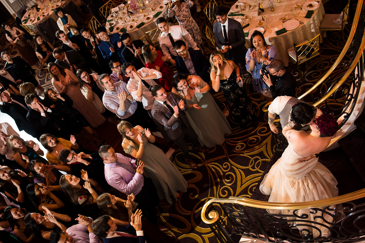 fun, unique image of the bride and groom kissing at the bottom of the staircase as they walk into their wedding reception at the palace at somerset park