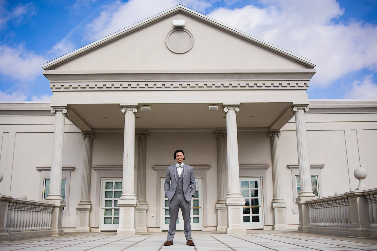 vibrant, colorful, airy photo of the groom standing outside in front of the wedding venue before their wedding ceremony in new jersey 