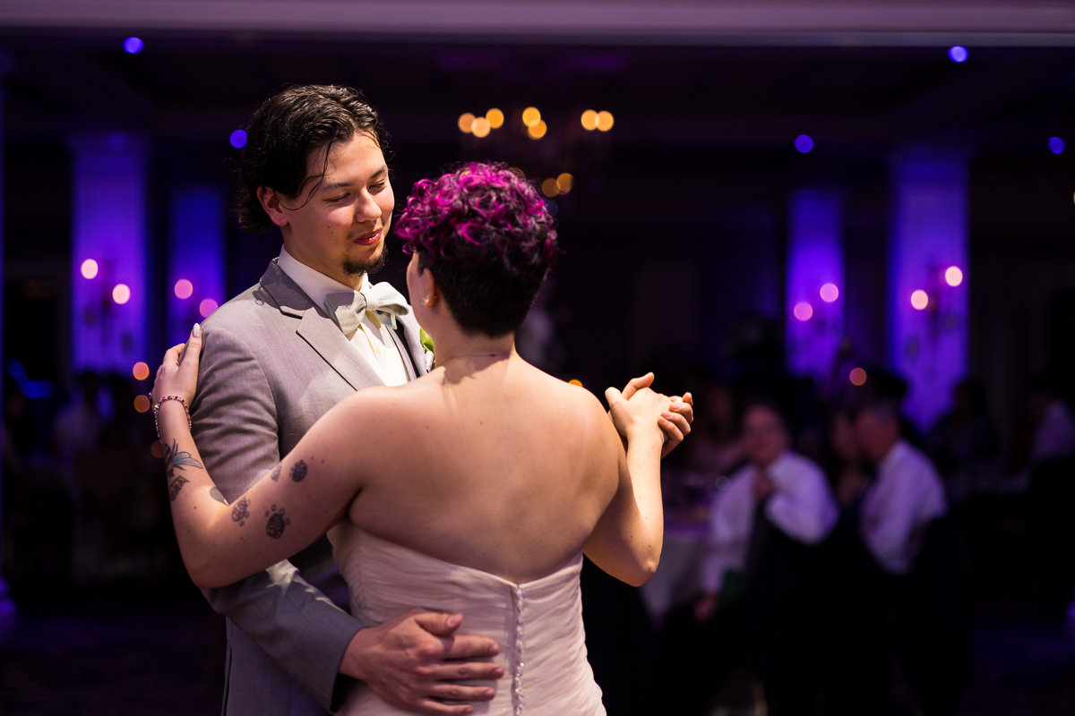 Palace at Somerset Park Wedding photographer, lisa rhinehart captures the bride and groom having their first dance with purple colorful, vibrant lights behind them 