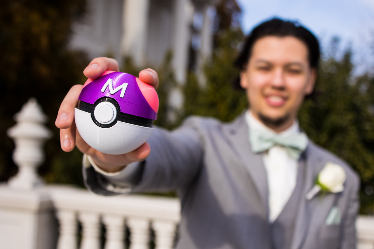 colorful, vibrant image of the groom holding a Pokeball which was the couples ring box for their unique and creative pokemon wedding at the palace in new jersey 