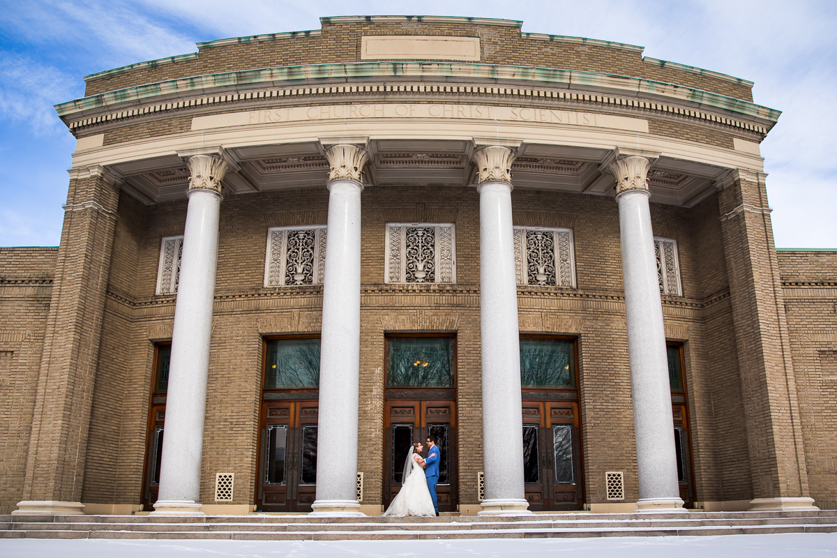 unique photo of the couple standing outside their venue getting photos taken before their Rochester NY wedding