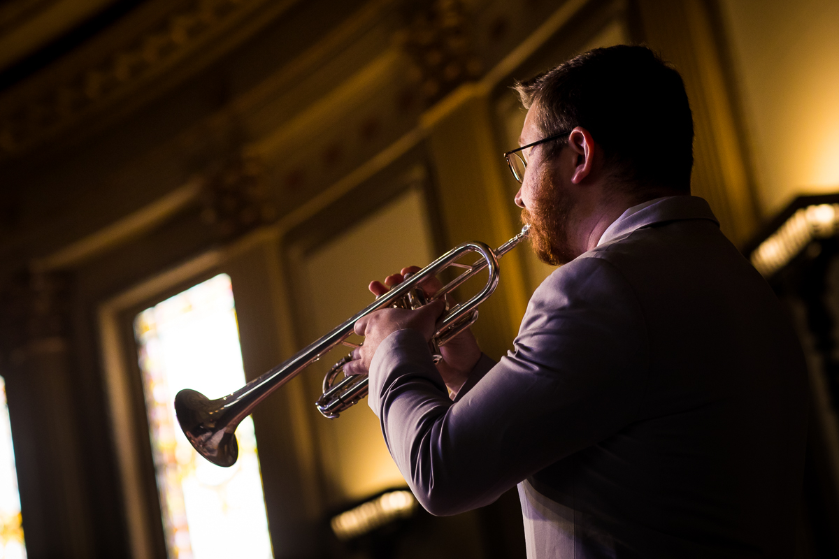image of the brides brother playing the trumpet during their wedding ceremony with photography done by creative photographer lisa rhinehart