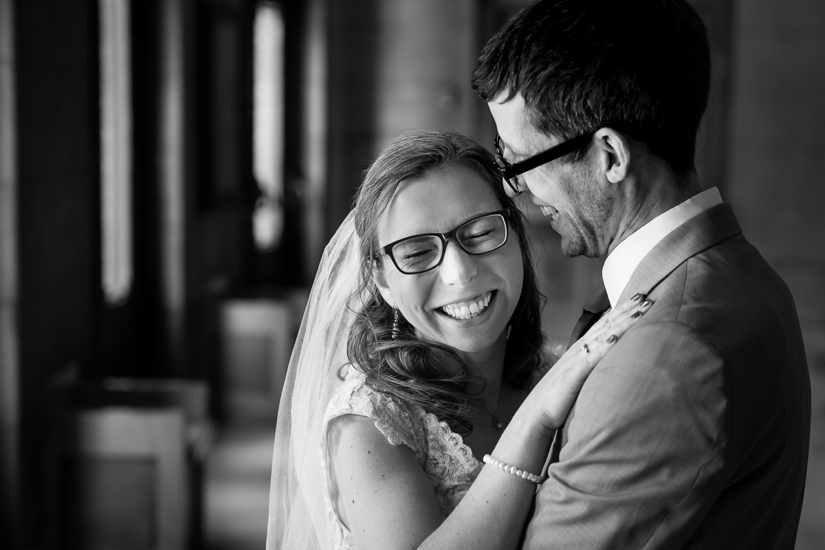 black and white photo of the bride and groom hugging one another laughing and smiling after their wedding ceremony in Rochester NY