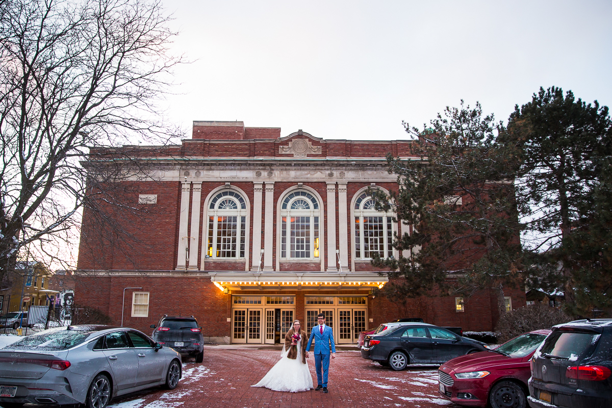 behind the scenes photo of the couple standing outside of their venue as they get pictures taken by wedding photographer lisa rhinehart photography