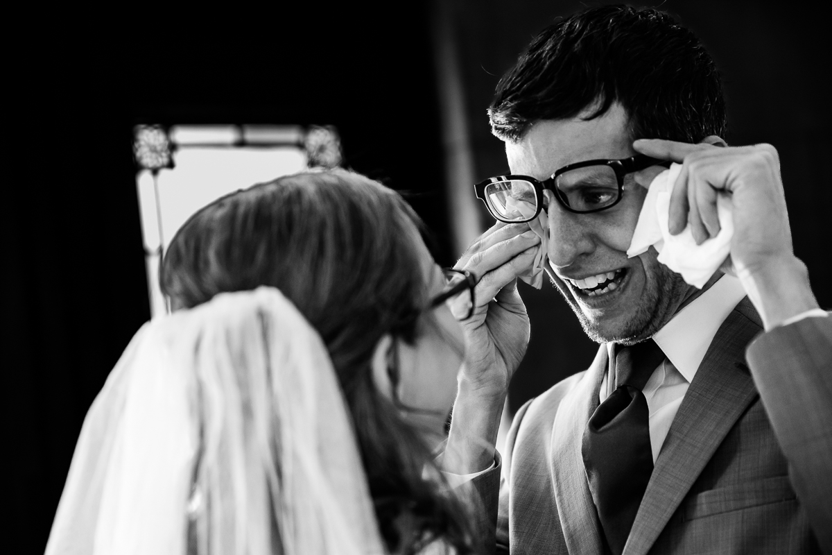 black and white image of the groom wiping away tears before his Rochester NY wedding