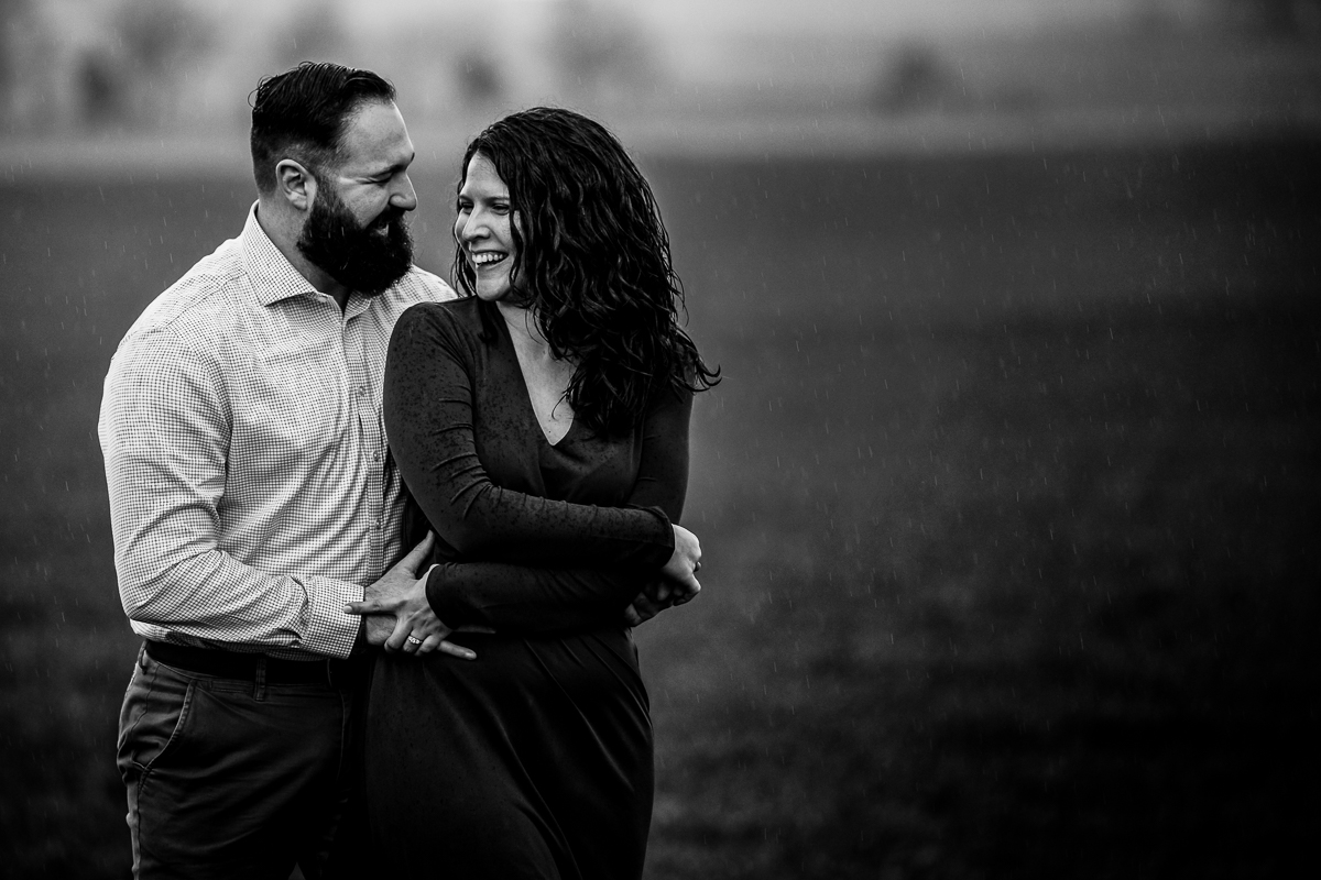 Black and white image of the couple laughing and smiling while embracing one another in their arm during this Rainy Pen Mar Engagement session
